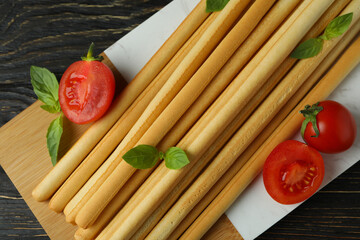 Board with grissini breadsticks on wooden table