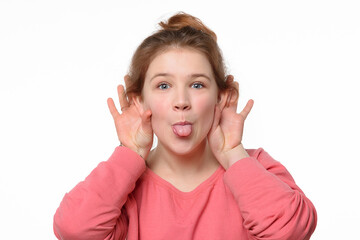 Close-up portrait of cheerful young girl making funny face and showing her tongue. White background