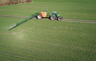 Luftbild - Traktor mit Pflanzenschutzspritze in einem jungen Getreidebestand im Einsatz,...