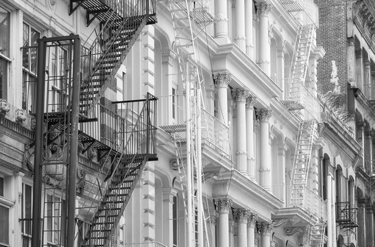 Row of old building with iron fire escapes, black and white picture of New York cityscape, USA.