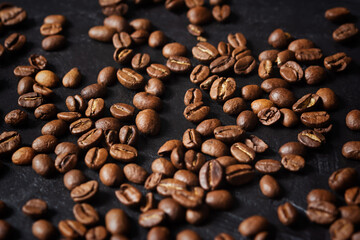 Coffee grain black background top view. Textured background for the design. Brown roasted macro beans scattered on the table in natural sunlight. Full frame, copy space. Beans for making espresso