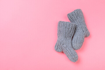knitted baby booties on pastel pink background.