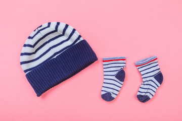 baby hat and little socks on pastel pink background .
