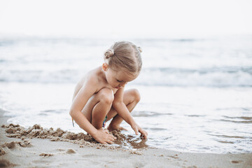 Fototapeta na wymiar child playing with wet sand by the ocean