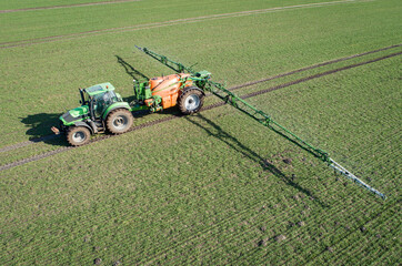 Luftbild - Traktor mit Pflanzenschutzspritze in einem jungen Getreidebestand im Einsatz, landwirtschaftliches Symbolfoto.