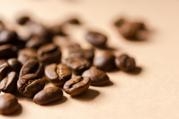 Coffee grain beige background top view. Textured background for the design. Brown roasted macro beans scattered on the table in natural sunlight. Full frame, copy space. Grains for making cappuccino