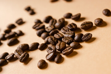 Coffee grain beige background top view. Textured background for the design. Brown roasted macro beans scattered on the table in natural sunlight. Full frame, copy space. Grains for making cappuccino