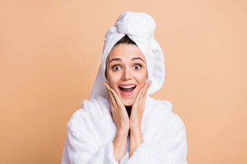 Photo of attractive amazed young woman hold hands cheekbones wear bathrobe isolated on beige color background