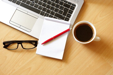 Laptop with coffee cup, notebook, glasses and pen on wooden background Top view. Concept for home office. Business concept. Work from home. Education background concept.