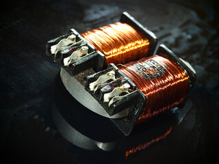 Burnt power transformer with copper winding on black background. 