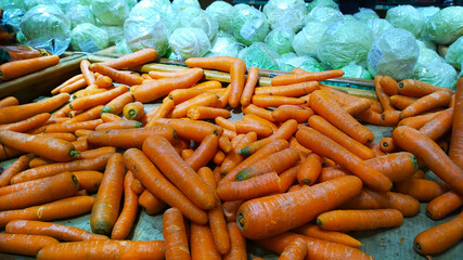 Pile of carrots and cabbage background. Grocery store. Shelves with organic natural vegetables in supermarket or farmer market. Fresh food. Retail industry. Discount and sale price. Greengrocer. Shop.