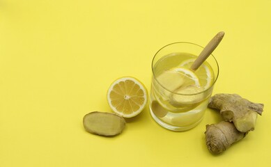 Winter cold cure infusion of lemon and fresh ginger on yellow background