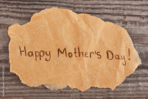 Concept of greeting Happy Mother's Day on old wooden background.