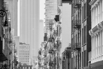Black and white picture of New York cityscape with old buildings with iron fire escapes, USA.