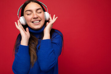 Photo of beautiful happy smiling young brunette woman wearing blue sweater isolated over red...