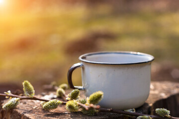Enamel cup of coffee or tea, on a wooden board in a summer forest outdoors. Place for your text. 