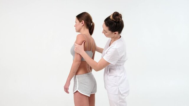 Physical Therapist Massaging Shoulder of a Female Patient. Over shoulder view of masseur performing deep tissue massage. 4k stock footage. close up video on white background