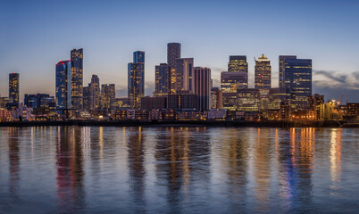 The financial district of London, Canary Wharf, with the illuminated, cooperate skysrcapers during evening time