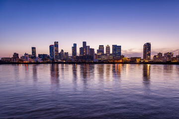 Fototapeta na wymiar Wide panoramic view over the Thames river to the new skyline of the financial district Canary Wharf in London, United Kingdom, during dusk