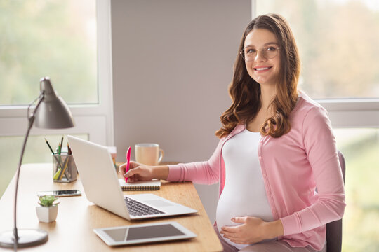 Profile side view portrait of lovely cheerful pregnant girl staying home writing esssay homework article prenatal in flat house indoors