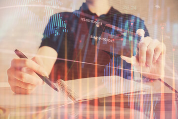 Double exposure of man hands holding a credit card and Forex graph drawing. Stock trading and digital fintech in Internet E-commerce concept.