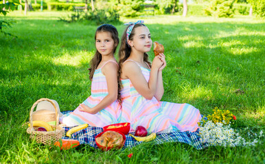 Family picnic. Little girls eat picnic meal on green grass. Summer vacation. Eating outdoors. Enjoy the day with tasty food