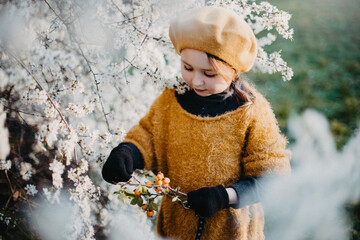 Little girl in early spring with flowering trees