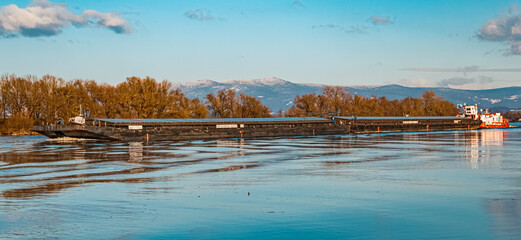 Beautiful winter landscape with a cargo ship, reflections and the Bavarian forest in the background at Stephansposching, Danube, Bavaria, Germany