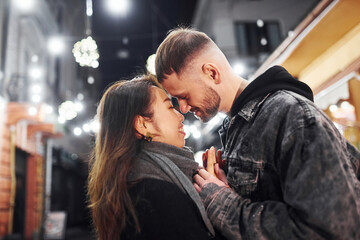Naklejka premium Embracing each other. Happy multiracial couple together outdoors in the city celebrating New year