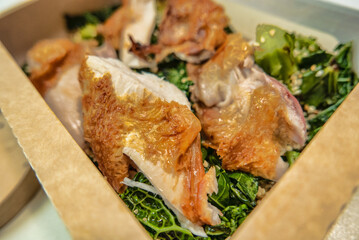 Organic chicken dish served with broccoli and sesame seeds in degradable packaging for delivery
