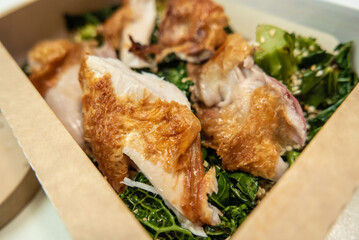 Organic chicken dish served with broccoli and sesame seeds in degradable packaging for delivery