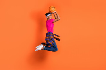 Fototapeta na wymiar Full length body size side profile photo of guy jumping playing basketball throwing smiling isolated bright orange color background