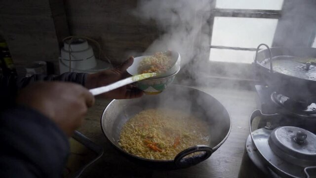 Unrecognized person serving hot noodles in bowl in rural kitchen, slow motion