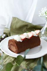 Chocolate Swiss Roll Cake with Chocolate cream filling and Strawberry set on cafe table.