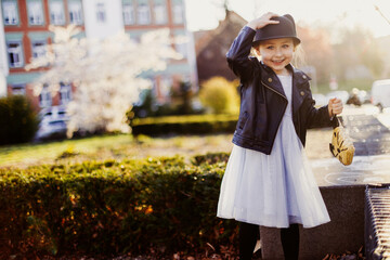 Smiling little girl with a cat hat walking in the city in sunny weather