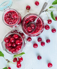 Cherry jam with fresh cherries on a blue background.Top view