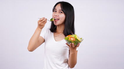 Young asian woman happy eating healthy salad with isolated white background