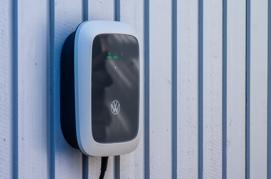 ID Charger EV wallbox installed on a wooden panel wall.