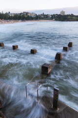 Coogee Beach rock pool on high tide with wave water coming in.