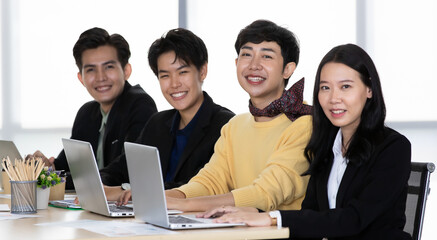 Fototapeta premium A group of multi-sex colleagues businesspeople, tomboy and transgender gay, working together with happy and intimate manner with laptop notebook computer in office