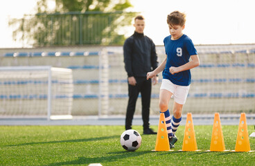 Sporty Soccer Boys Running Ball on Training Drill. Young Coach Watching Youth Football Team Practice Session. Kid Kicking Soccer Ball on Soccer Training Camp