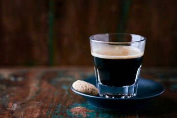 Coffee in glass cup on rustic wooden background. Close up.