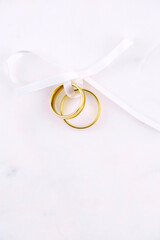 Two golden wedding rings close up with ribbon on white background. Wedding invitation card concept. 