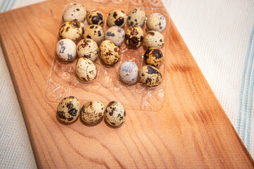 fresh quail eggs in a plastic box on a wooden board, quail eggs for a delicious Easter holiday in a tray, preparation for Easter, healthy dietary food, diet