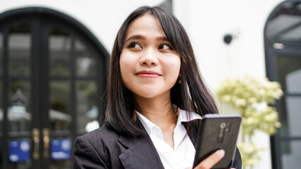 Beautiful young asian business woman in suit standing at cafe with phone and Brown envelope