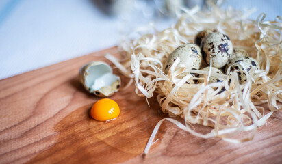 fresh quail eggs on a wooden board, quail eggs for a delicious easter holiday, raw homemade quail egg smashed on a kitchen board, raw yolk and egg white