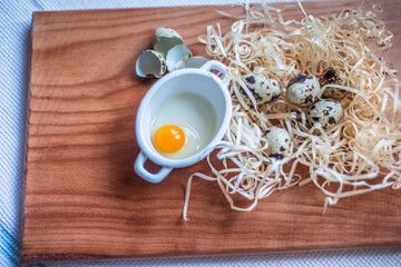 quail eggs for a delicious easter holiday, raw homemade quail egg in a ceramic bowl on a kitchen board, raw yolk and egg white, cooking healthy food