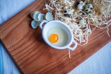 quail eggs for a delicious easter holiday, raw homemade quail egg in a ceramic bowl on a kitchen board, raw yolk and egg white, cooking healthy food