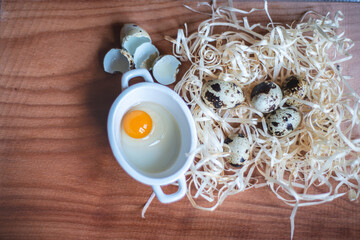 quail eggs for a delicious easter holiday, raw homemade quail egg in a ceramic bowl on a kitchen board, raw yolk and egg white, cooking healthy food