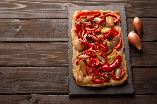 Spanish coca with onion and bell pepper on a dark wooden background with copy space